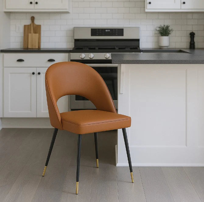 Elevate your seating with this sophisticated Venice chair, crafted from durable polyurethane upholstery in a warm tan finish. The sleek black legs are accented with refined gold feet, creating a striking contrast that complements contemporary and transitional interiors alike. Designed for both aesthetic appeal and everyday comfort, this chair delivers the perfect balance of style and functionality. Its streamlined silhouette makes it an ideal addition to living rooms, bedrooms, or home offices where underst